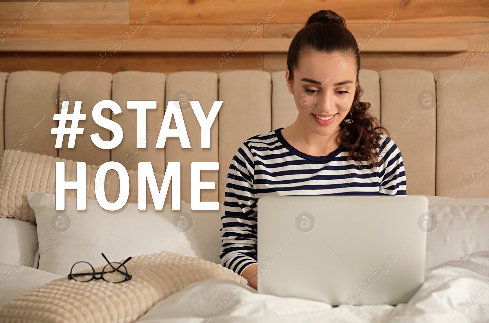 Image of Hashtag Stayhome - protective measure during coronavirus pandemic. Young woman working on laptop in bed