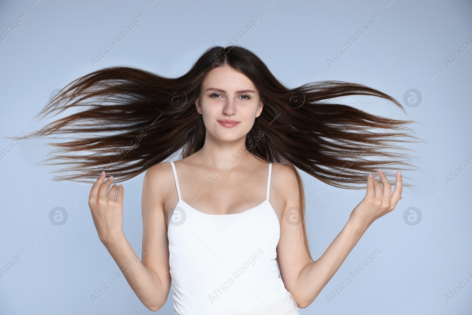 Photo of Young woman with strong healthy hair on light blue background