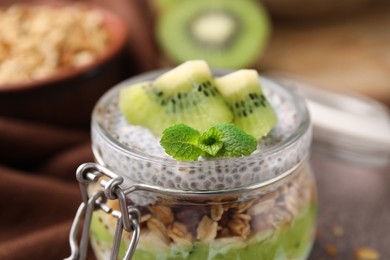 Photo of Delicious dessert with kiwi and chia seeds in glass jar, closeup