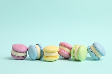 Photo of Delicious colorful macarons on light blue background, space for text