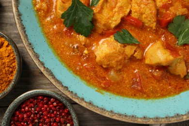 Photo of Delicious chicken curry and spices on wooden table, top view