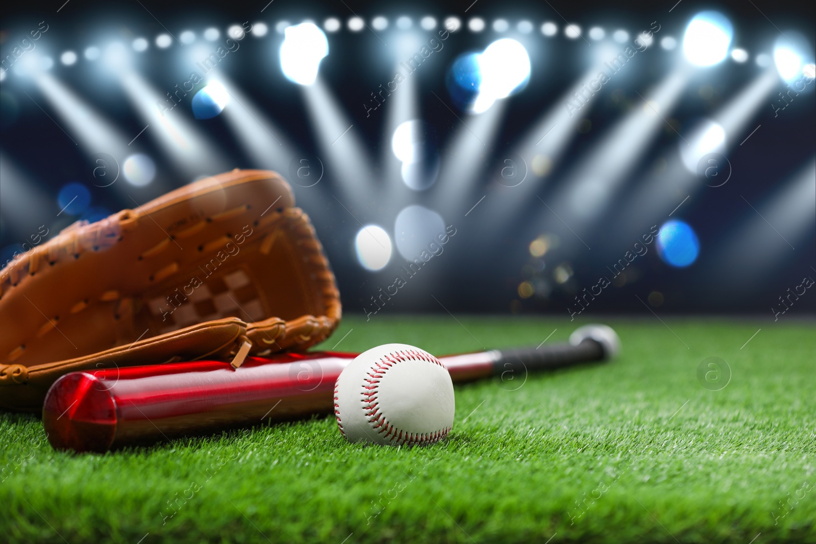 Image of Baseball bat, glove and ball on grass at stadium