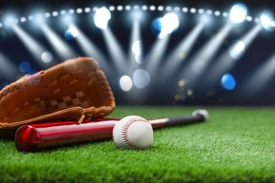 Baseball bat, glove and ball on grass at stadium