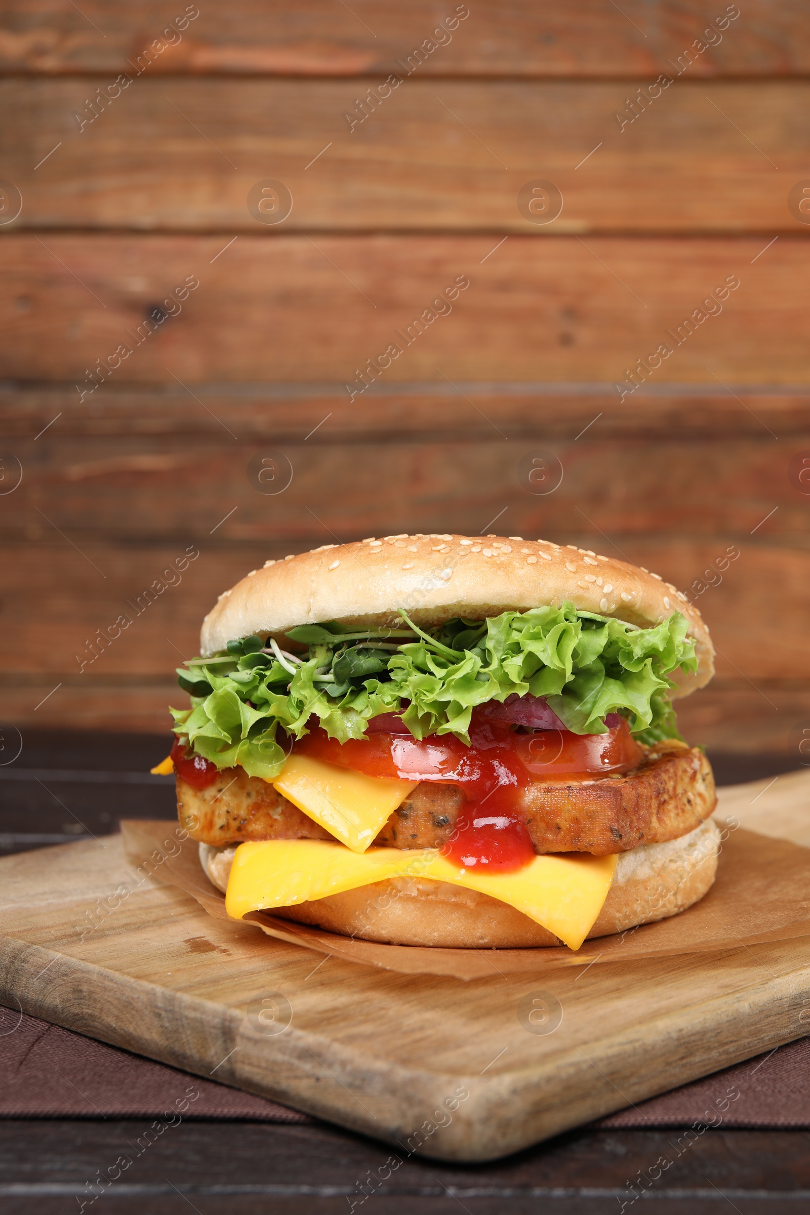 Photo of Delicious burger with tofu, fresh vegetables and sauce on wooden table