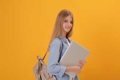 Photo of Teenage student with laptop and backpack on yellow background