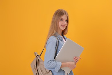 Teenage student with laptop and backpack on yellow background