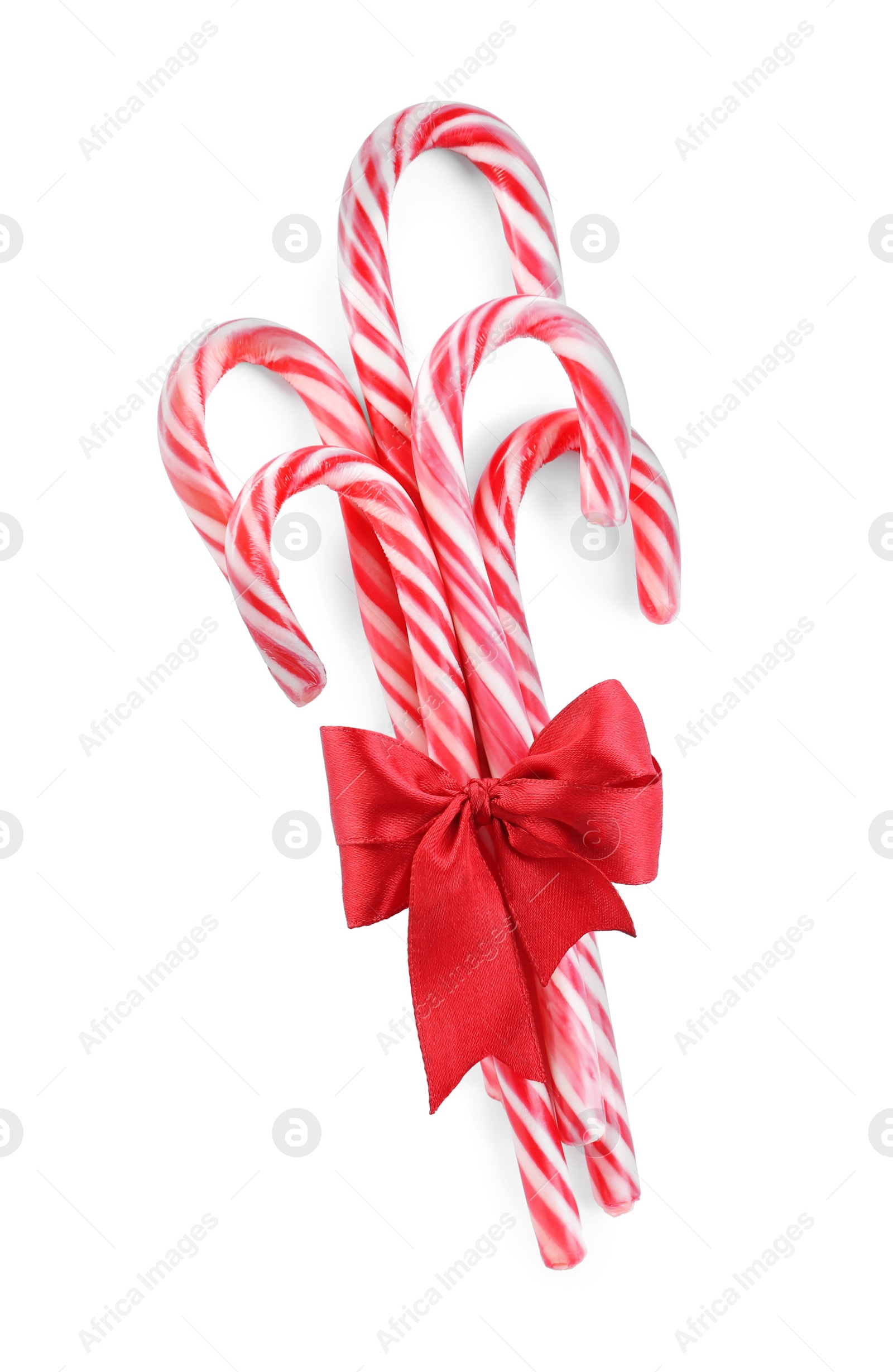 Photo of Sweet Christmas candy canes with red bow on white background, top view