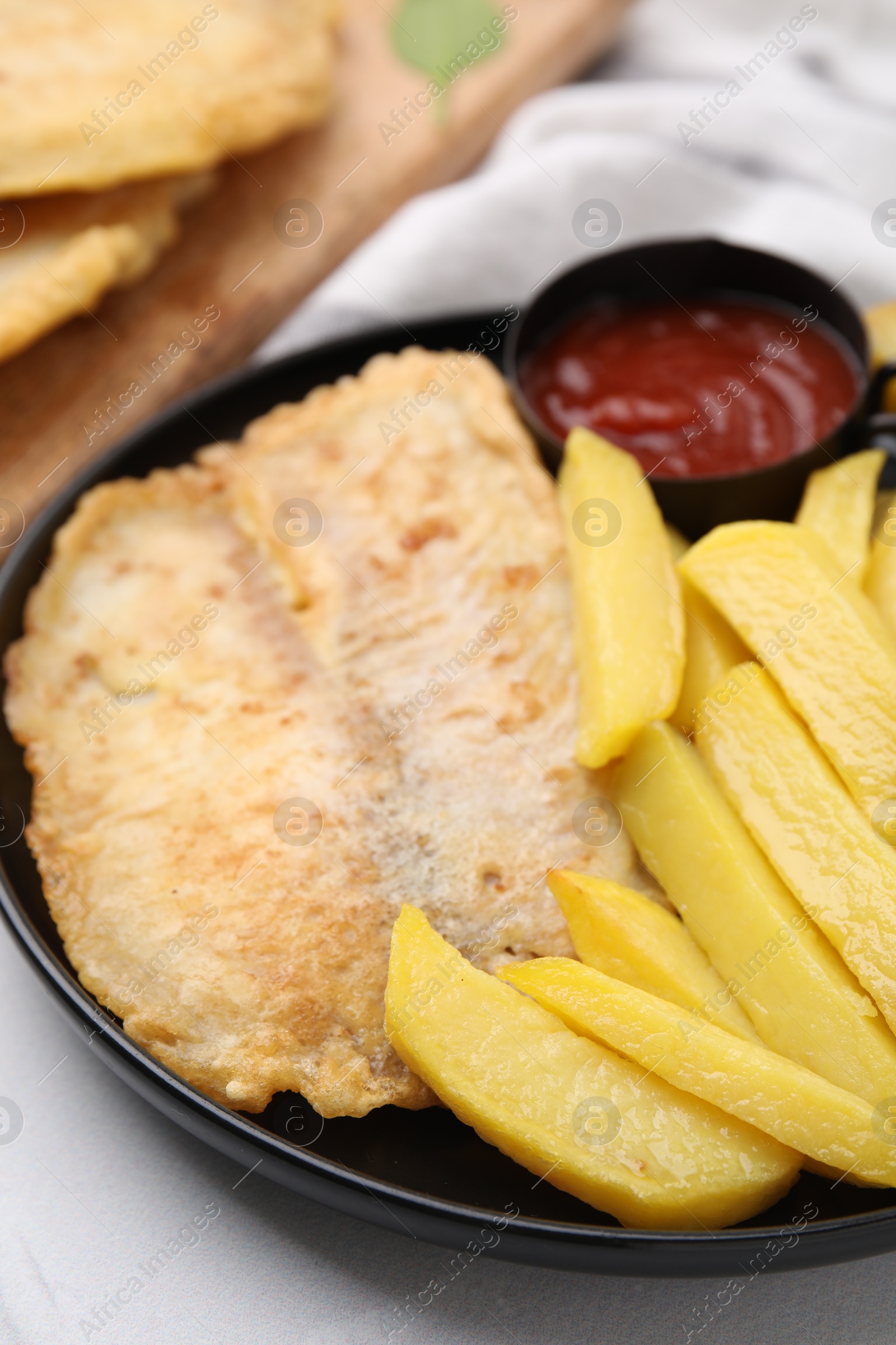 Photo of Delicious fish and chips with ketchup on light table, closeup