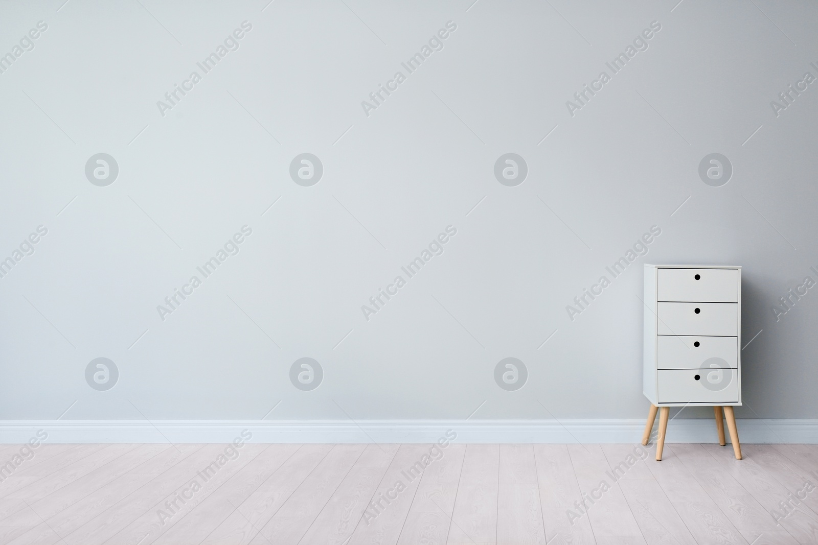 Photo of Living room interior with chest of drawers near light wall