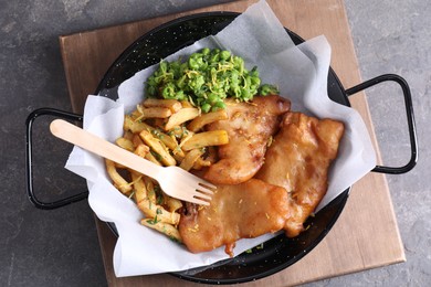 Photo of Tasty fish, chips and peas on grey table, top view