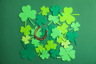Flat lay composition with clover leaves and horseshoe on green background. St. Patrick's day