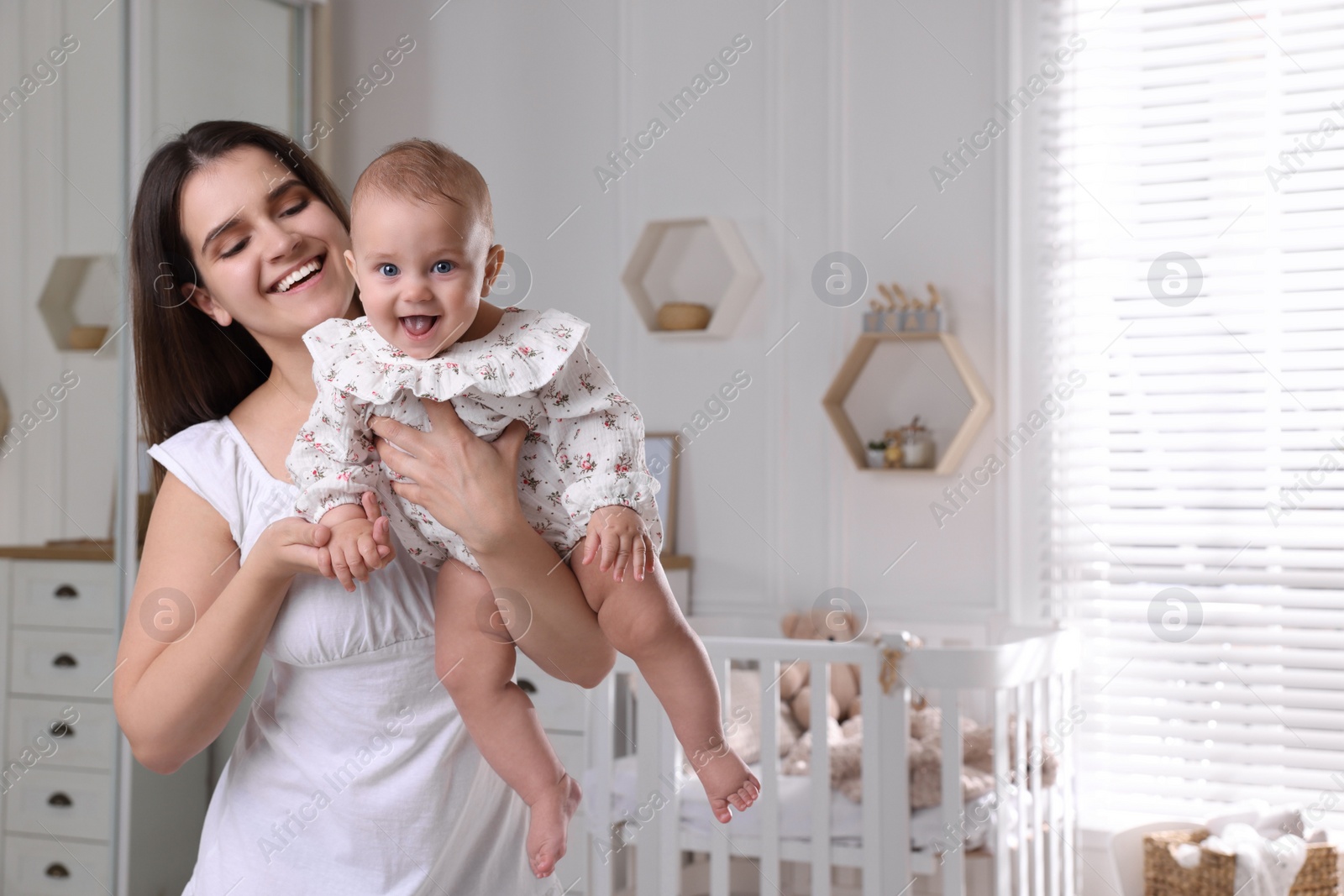 Photo of Happy young mother with her baby daughter in nursery. Space for text