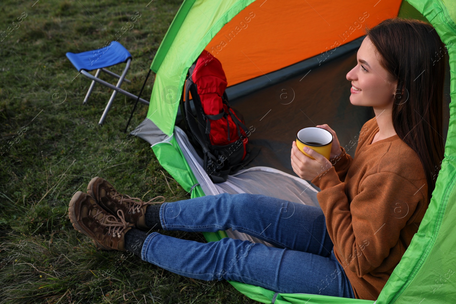 Photo of Young woman with cup of drink in camping tent outdoors