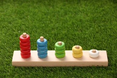 Photo of Stacking and counting game wooden pieces on artificial grass, space for text. Educational toy for motor skills development