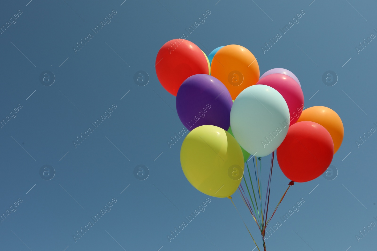 Photo of Bunch of colorful balloons against blue sky. Space for text