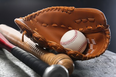 Baseball bats, glove and ball on grey table, closeup
