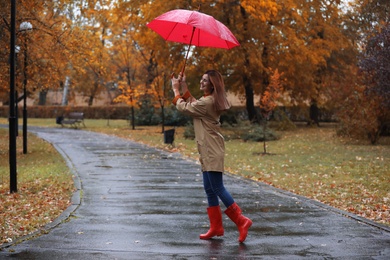 Photo of Woman with umbrella taking walk in autumn park on rainy day