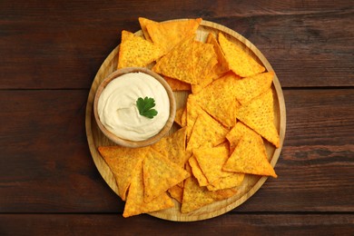 Photo of Delicious hummus served with nachos on wooden table, top view