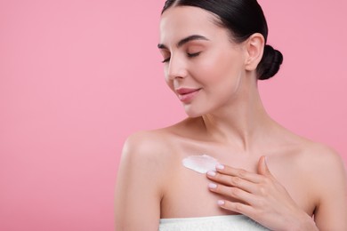 Photo of Woman with smear of body cream on her chest against pink background, space for text