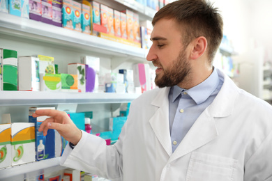 Professional pharmacist near shelves in modern drugstore