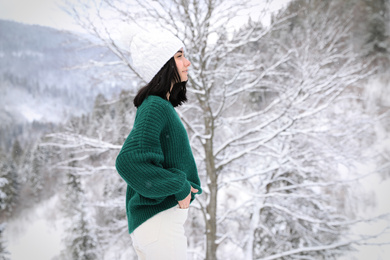 Photo of Pretty woman wearing warm sweater in winter forest