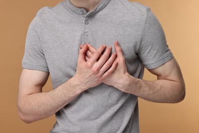Photo of Man suffering from heart hurt on beige background, closeup