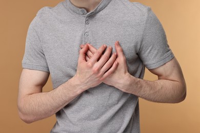 Man suffering from heart hurt on beige background, closeup