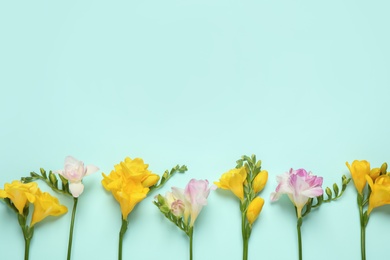 Photo of Beautiful blooming freesias on light background, flat lay. Space for text