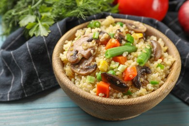 Photo of Delicious bulgur with vegetables and mushrooms on light blue wooden table, closeup