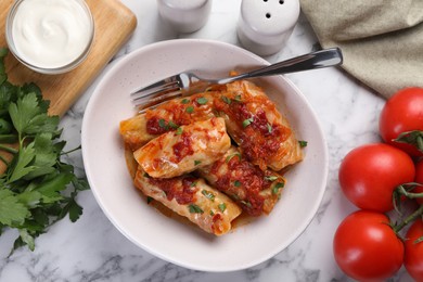 Photo of Delicious stuffed cabbage rolls cooked with homemade tomato sauce on white marble table, flat lay