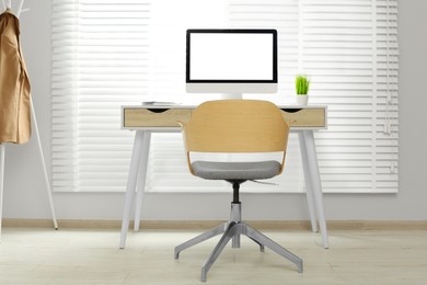 Stylish office interior with comfortable chair, desk and computer