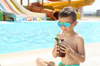 Boy with delicious refreshing drink in water park