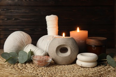 Photo of Aromatherapy. Scented candles, eucalyptus branches and spa products on wicker mat