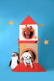 Photo of Cardboard rocket and different toys on light blue background