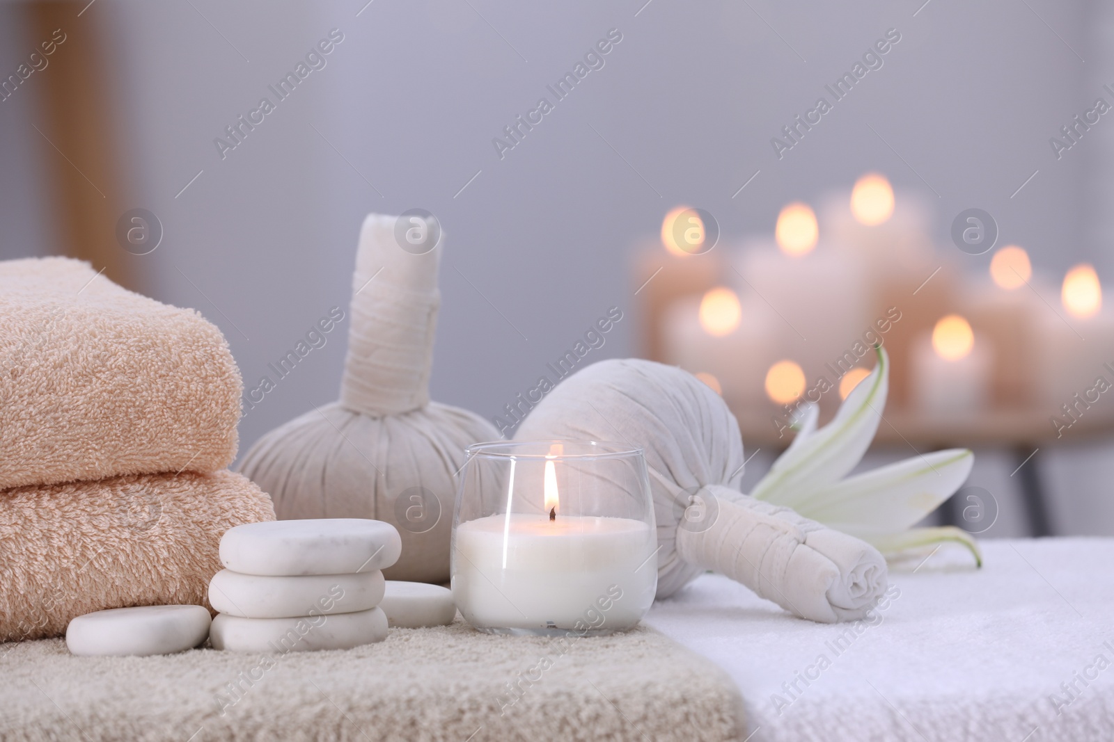 Photo of Spa composition with burning candle and herbal bags on massage table in wellness center