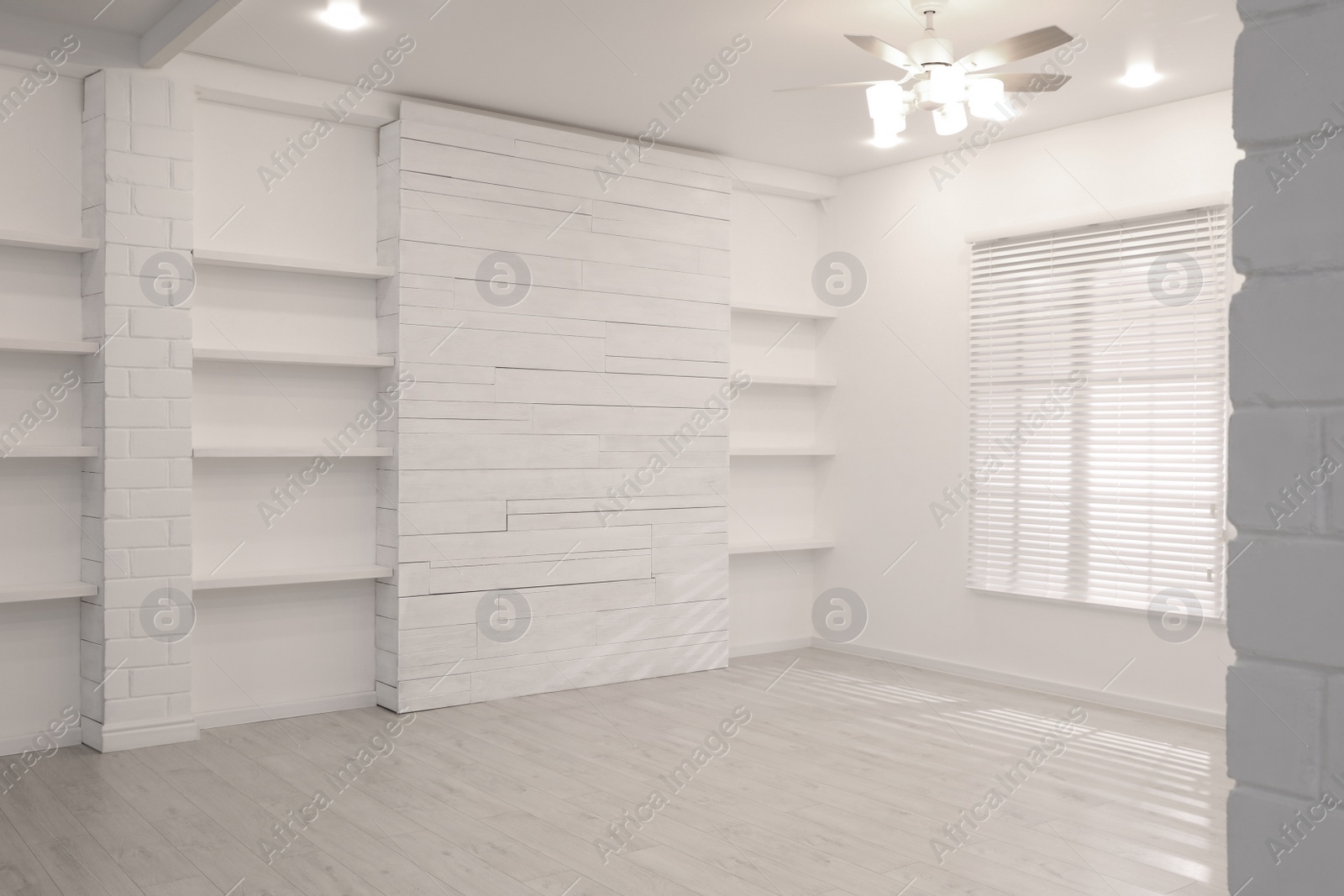 Photo of Empty room with textured wall, stylish wooden shelves and large window