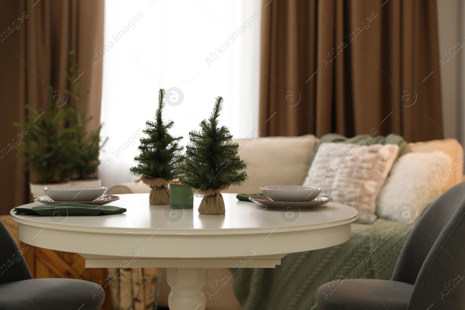 Photo of Small fir trees on dining table indoors. Christmas interior design