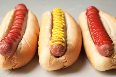 Photo of Fresh delicious hot dogs with sauces on table, closeup