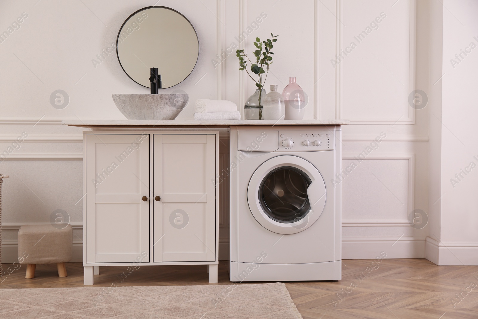 Photo of Laundry room interior with modern washing machine and stylish vessel sink on countertop