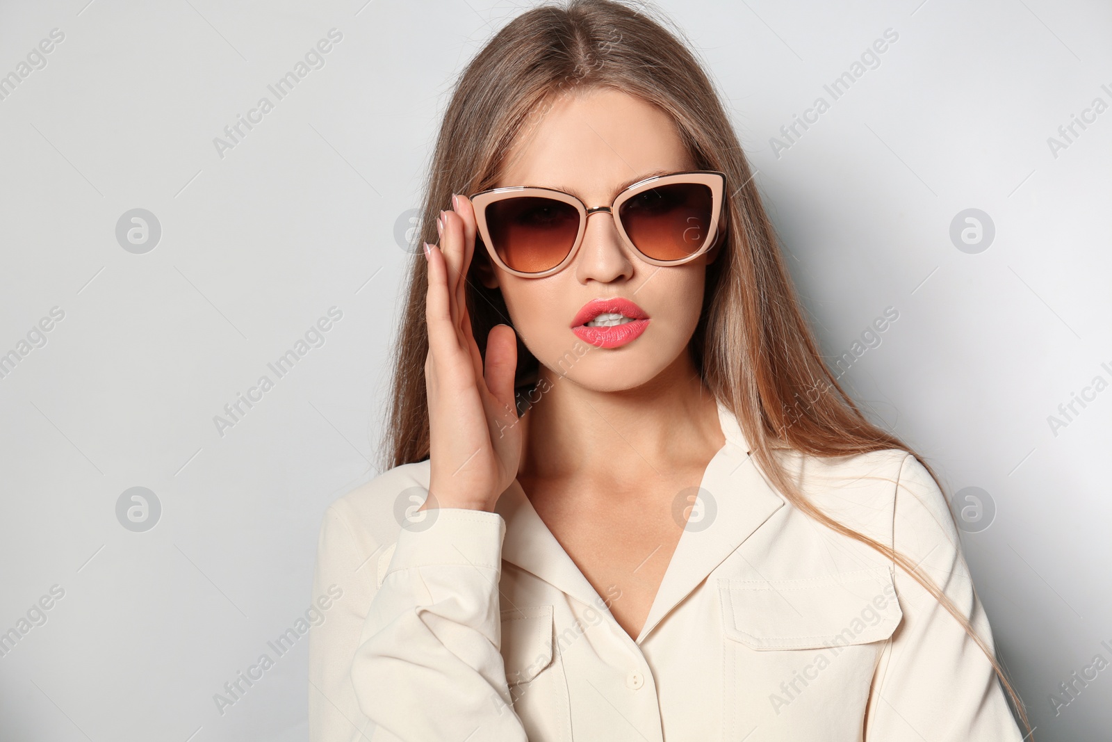 Photo of Young woman wearing stylish sunglasses on light background