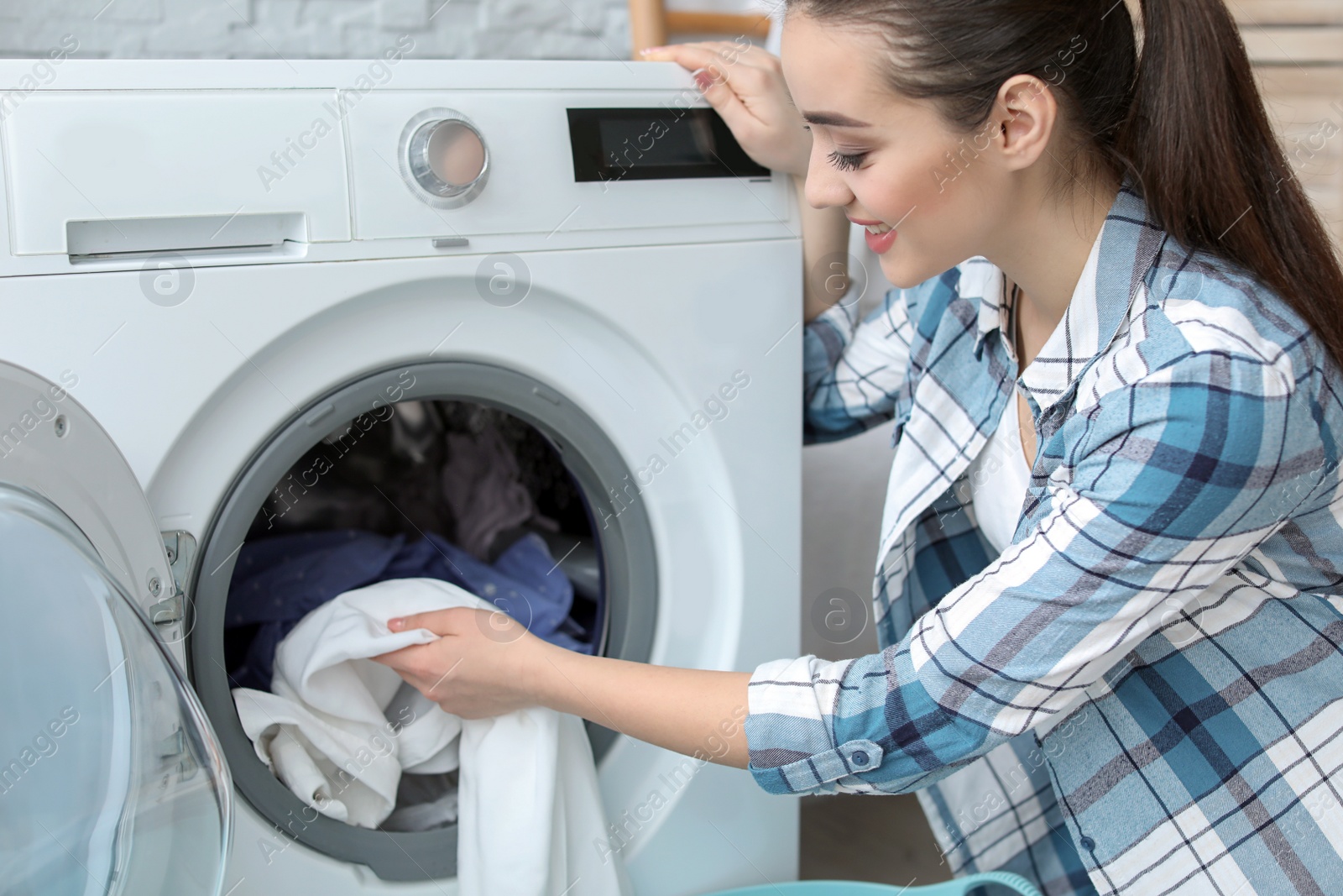 Photo of Young woman doing laundry at home