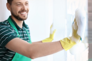 Male worker washing window glass at home