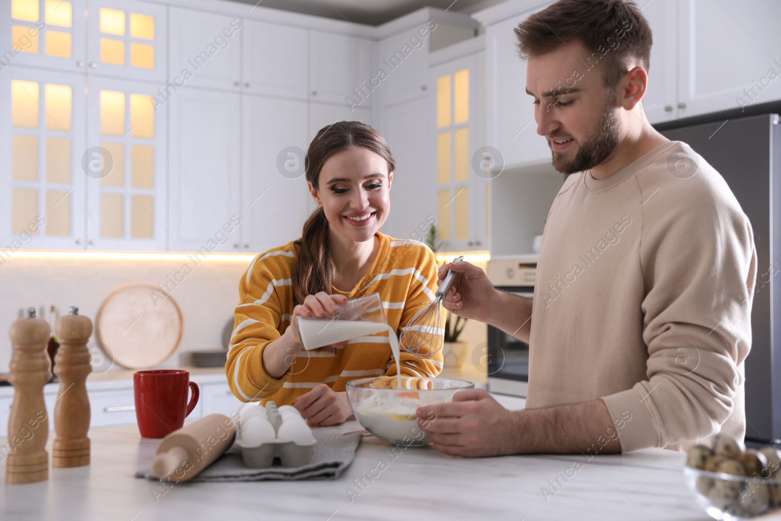 Photo of Lovely young couple cooking dough together in kitchen