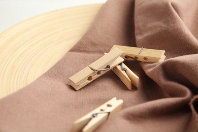 Many wooden clothespins on brown fabric, closeup view