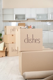 Photo of Cardboard boxes and adhesive tape dispenser in kitchen. Moving day