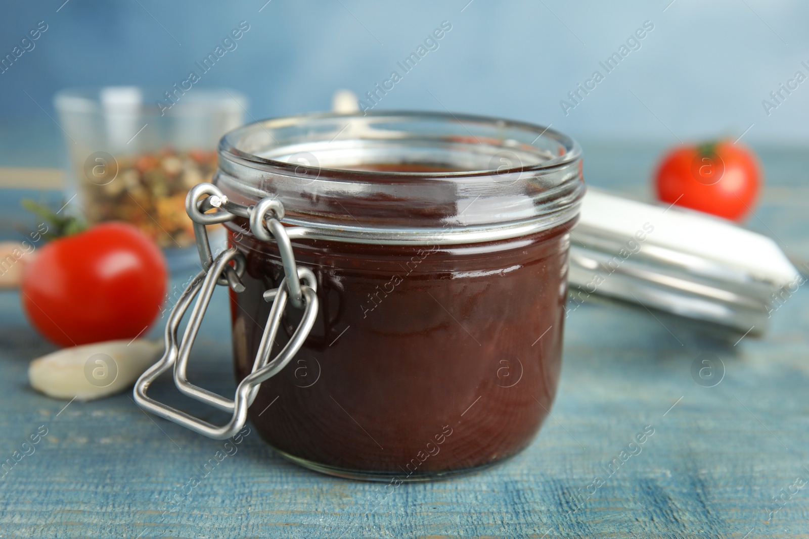 Photo of Jar with tasty barbecue sauce on blue wooden table