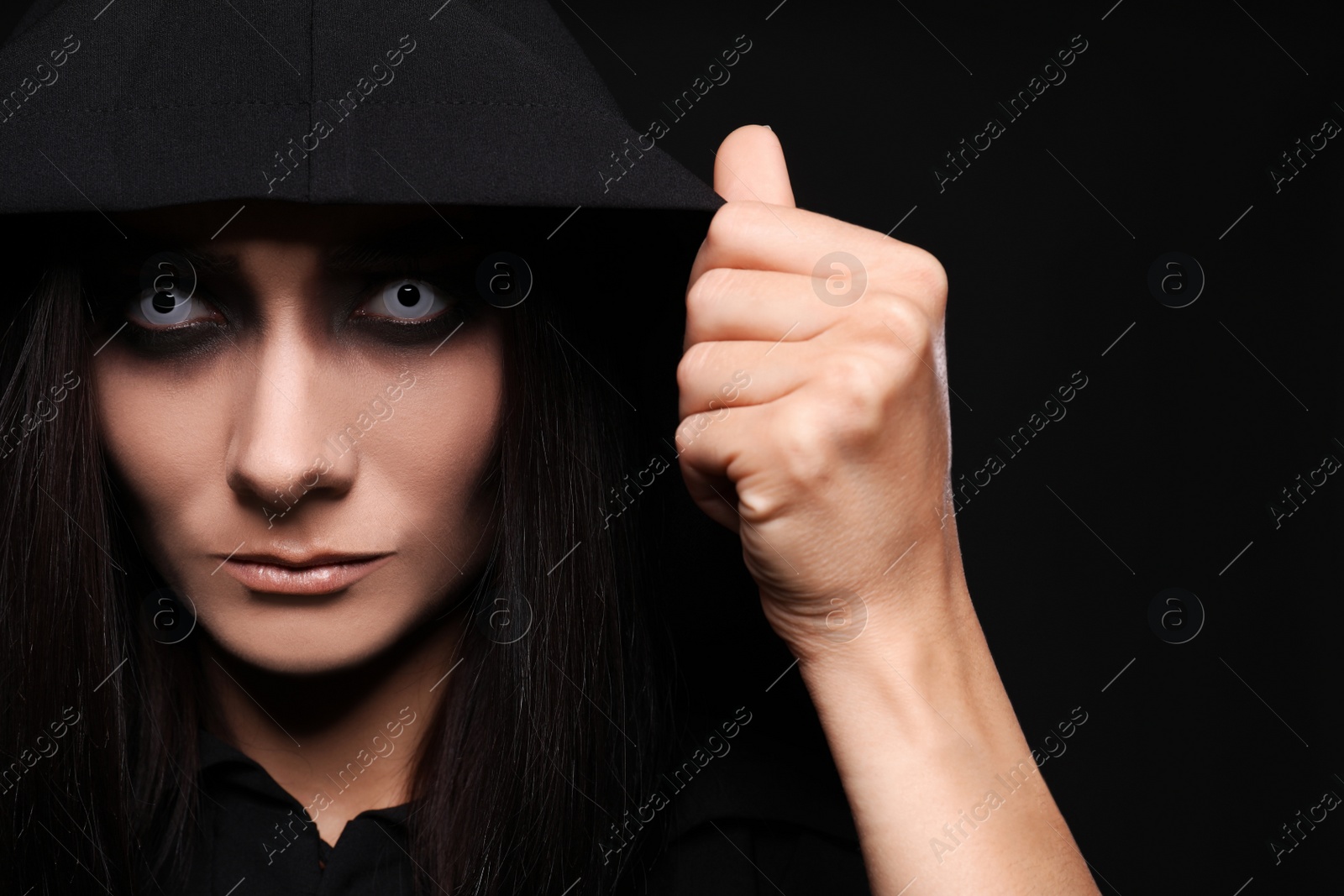 Photo of Mysterious witch with spooky eyes on black background, closeup