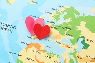 Honeymoon concept. Two red paper hearts on world map, top view