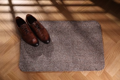 Photo of Stylish door mat with shoes on floor indoors, above view