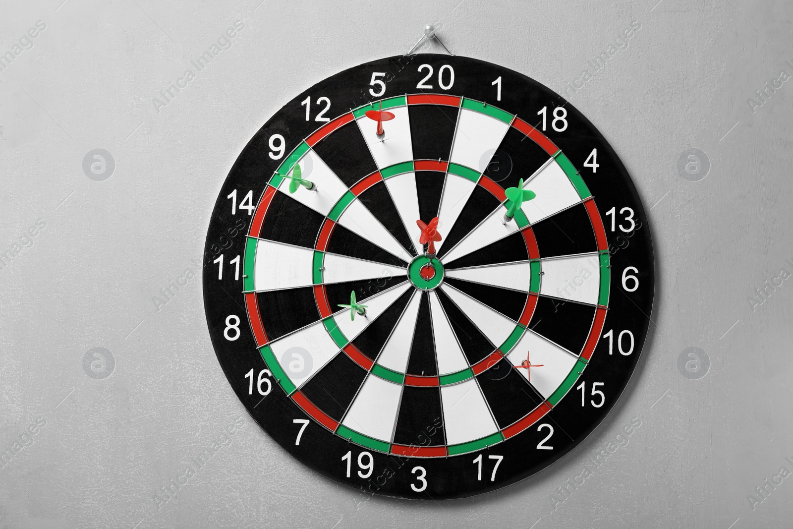 Photo of Arrows hitting dart board on grey concrete wall